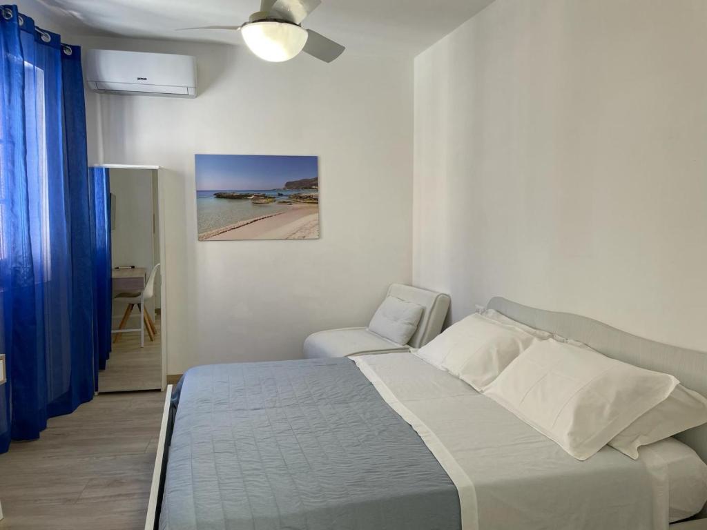 een witte slaapkamer met een bed en een stoel bij Casa dei Mulini in Favignana