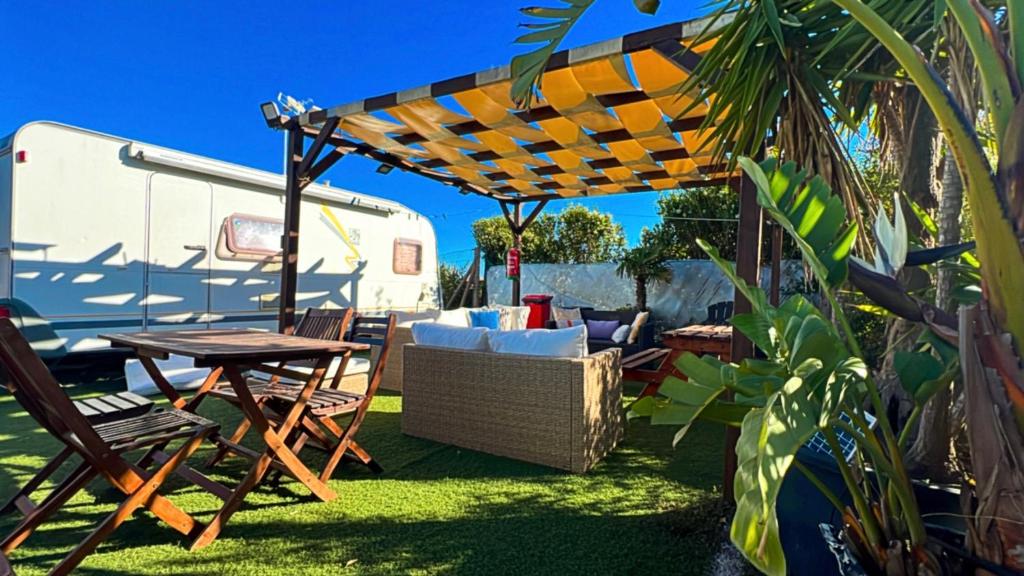 un patio con mesa, sillas y una cabaña en Caravanas Con Encanto El Palmar 2, en El Palmar