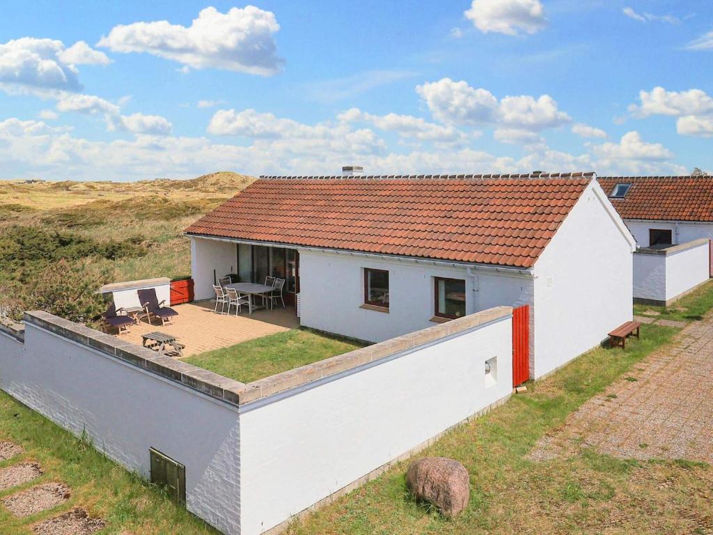 a white house with a roof on a field at 6 person holiday home in Pandrup in Rødhus