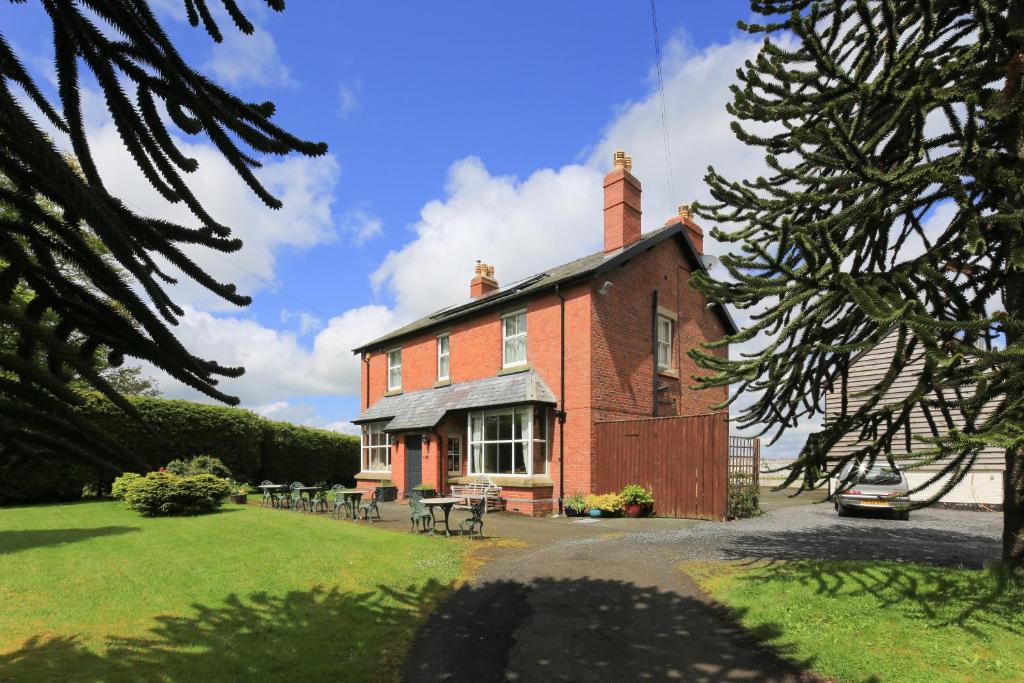 a red brick house with a picnic table in front of it at The Old Vicarage Dolfor in Newtown