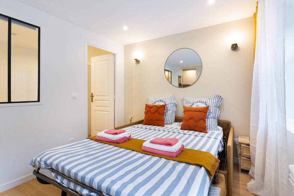 - une chambre avec un lit doté d'oreillers et d'un miroir dans l'établissement Appartement 2 pièces Boulogne Roland Garros, à Boulogne-Billancourt