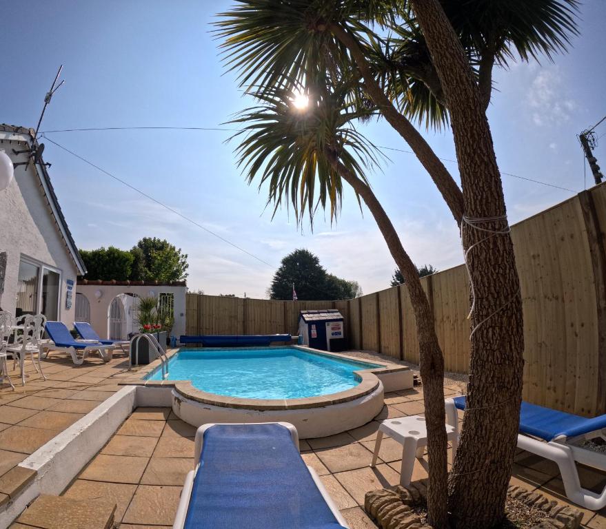 uma piscina num quintal com uma palmeira em Family Bungalow with Private Pool em Kilgetty