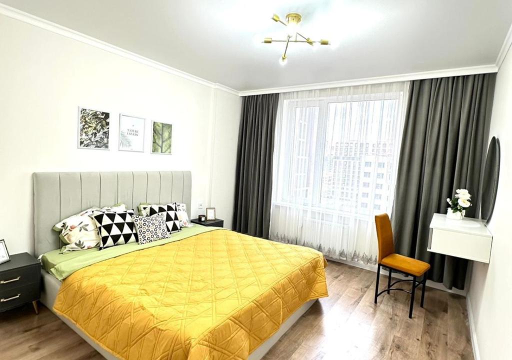 um quarto com uma cama amarela e uma janela em Шатёр у Хана, Квартира в Центре и у Хан-Шатыра em Astana