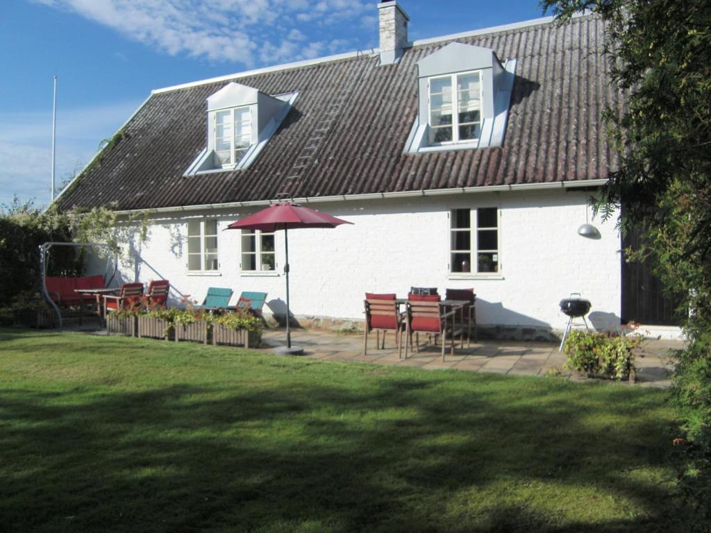 une maison blanche avec une table, des chaises et un parasol dans l'établissement Bräcke Gård, à Höganäs