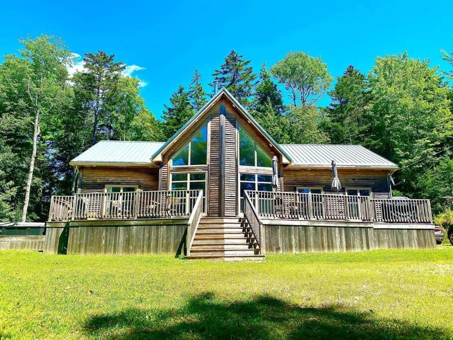 a log home with a large porch and a fence at Forest Fawn Chalet 2 Bed with Hot Tub in Sussex