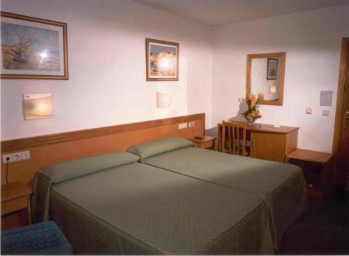 a bedroom with a bed and a desk and a mirror at Hotel San Vicente in Santiago de Compostela