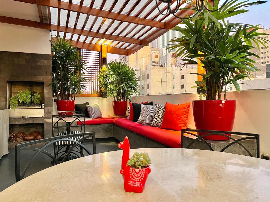 um pátio com um sofá vermelho, mesas e plantas em ANA FRANK Boutique Hotel em Lima