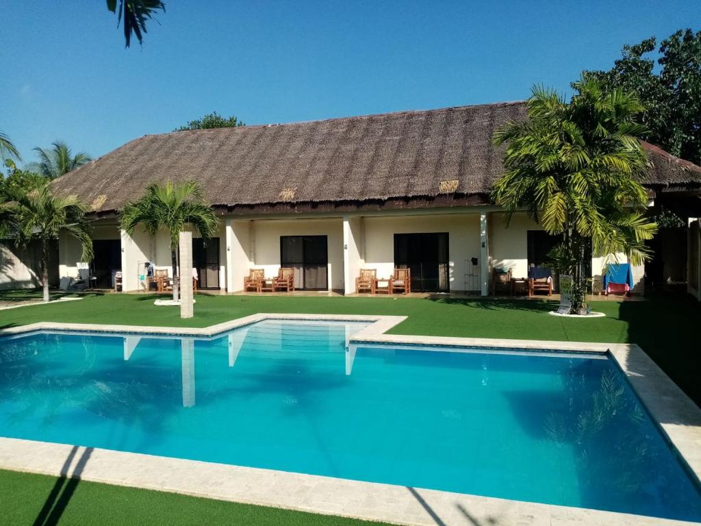 a villa with a swimming pool in front of a house at HIGALA Resort in Panglao