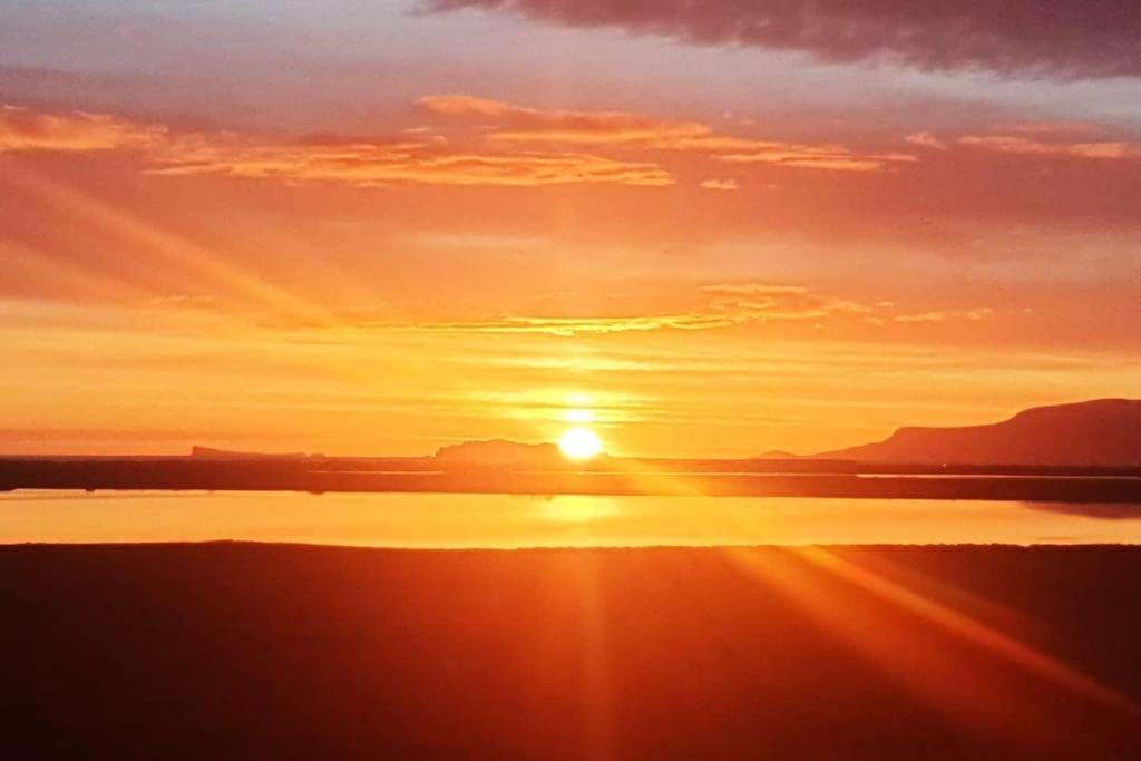 um pôr-do-sol com o pôr-do-sol sobre uma massa de água em Ibúð með einstöku útsýni em Sauðárkrókur
