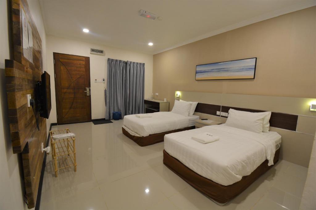 a hotel room with two beds and a television at Hemingway Cottage 海明威度假屋 in Semporna