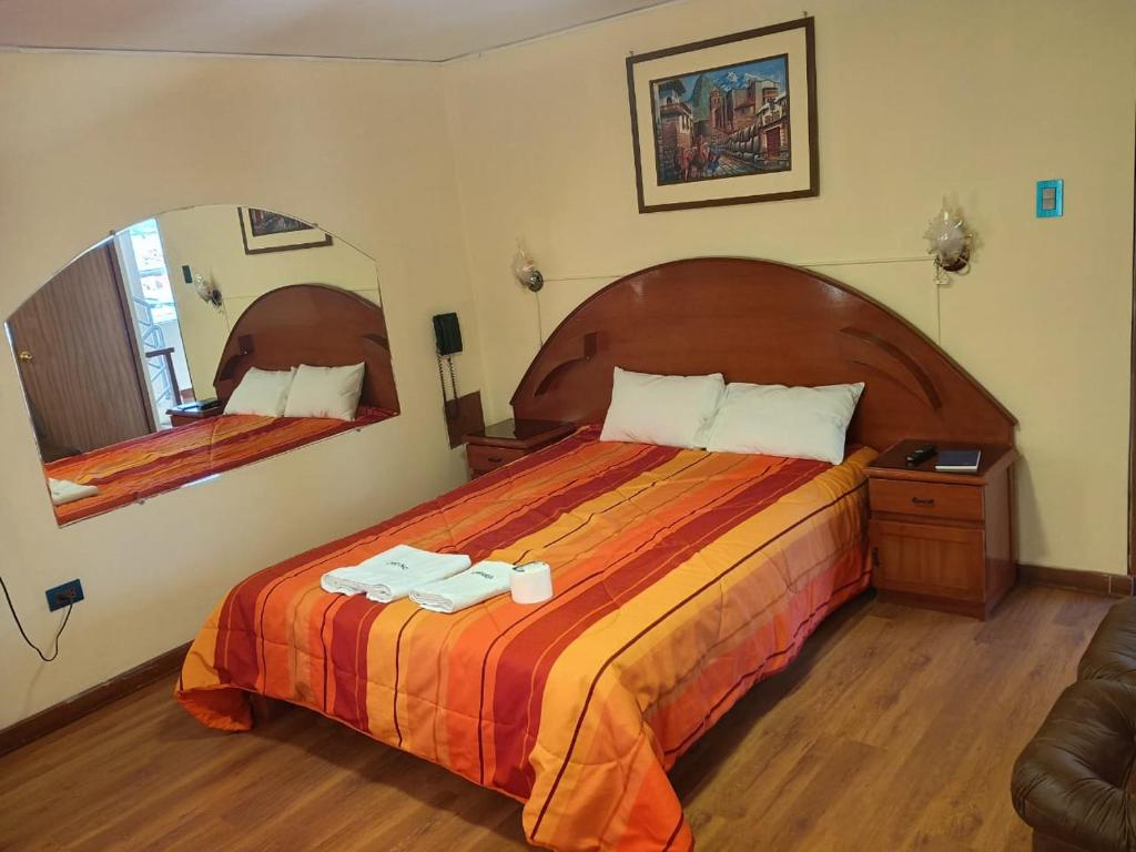 Cette chambre comprend un grand lit et un miroir. dans l'établissement Hostal Koricancha, à Sicuani