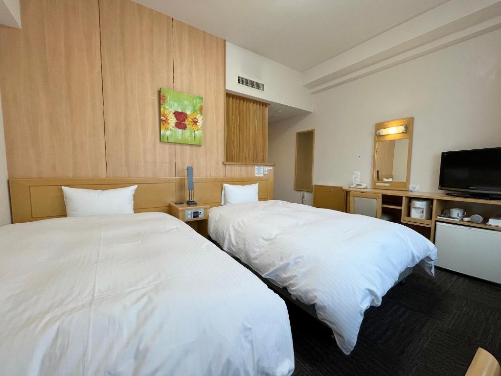 Habitación de hotel con 2 camas y TV de pantalla plana. en Hotel Route-Inn Kushiro Ekimae en Kushiro