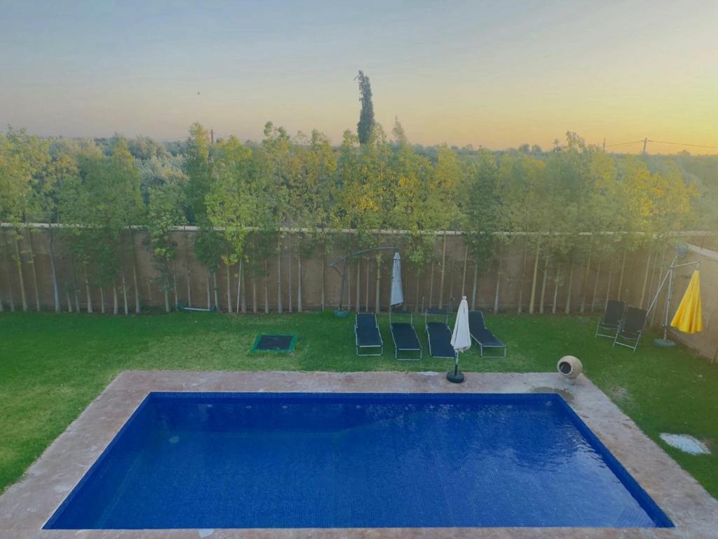 a swimming pool in a yard with chairs and an umbrella at Villa Salah in Marrakesh