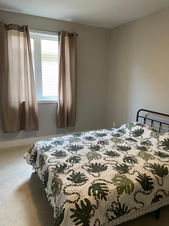 1 dormitorio con cama con edredón y ventana en Sweet home 24 en Ottawa
