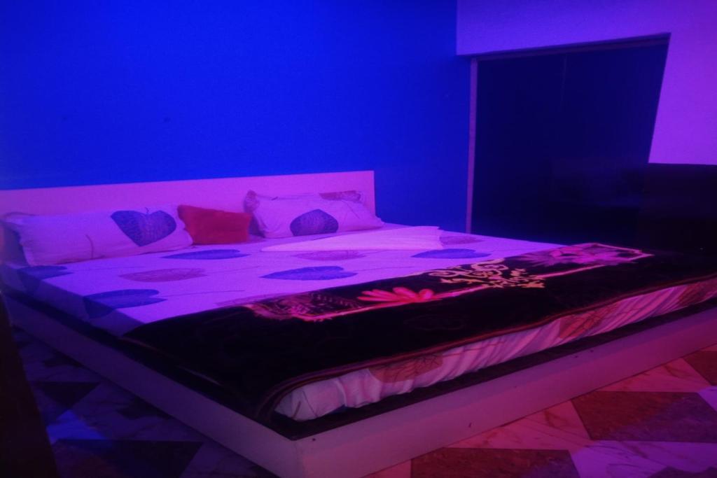 a bedroom with a bed with purple lights on it at OYO Hotel Rosewood in Palwal