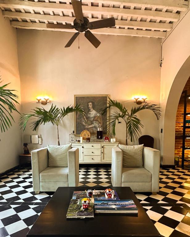 a living room with two chairs and a ceiling fan at Casa Charlotte - Alma Hotels in Santa Marta