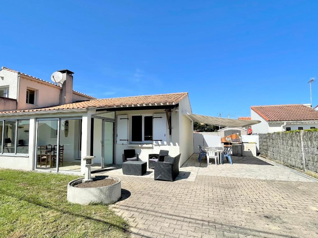 une terrasse d'une maison avec des chaises et des tables dans l'établissement Maison à 650m de la mer avec jardin, véranda et WIFI - FR-1-231-325, à Bretignolles-sur-Mer