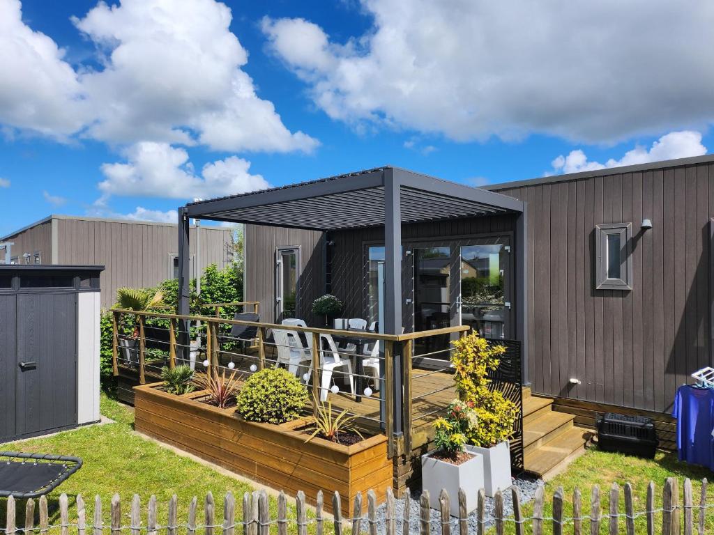 une maison dotée d'une terrasse avec un toit noir dans l'établissement Mobil-home luxueux à Jullouville, 200m plage, piscine chauffée, pour 6 personnes - FR-1-361A-73, à Jullouville