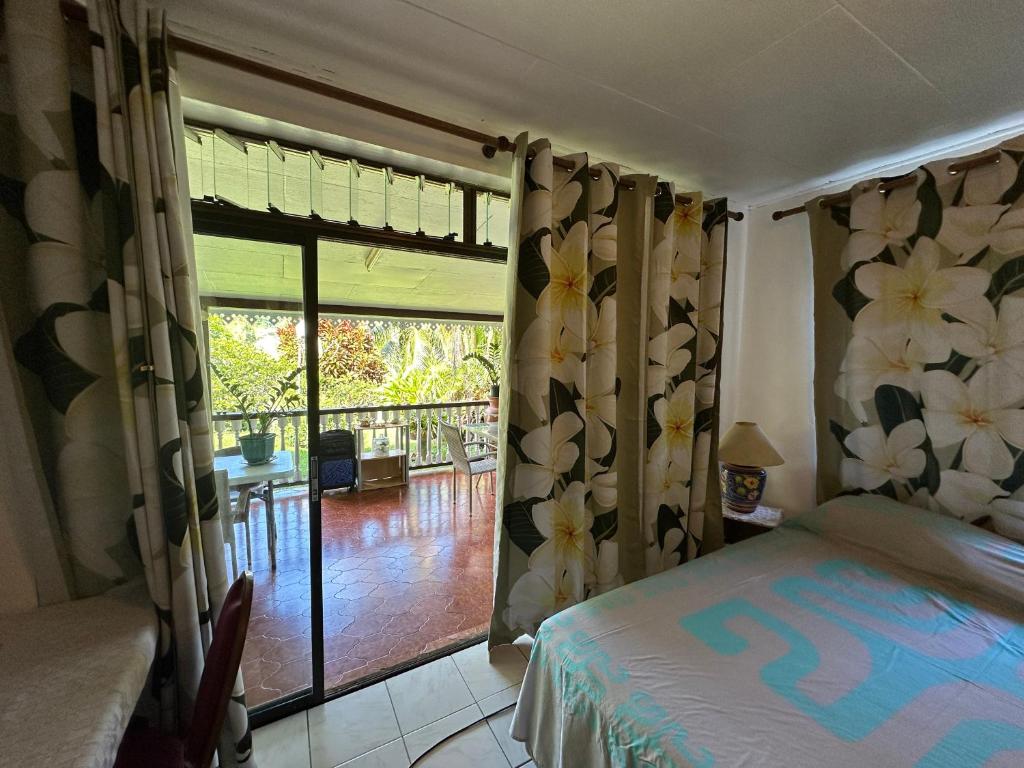 - une chambre avec un lit et une porte coulissante en verre dans l'établissement Chambre d'hôtes chez Anouk, à Tevaitoa