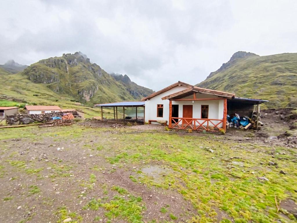 une maison sur une colline avec des montagnes en arrière-plan dans l'établissement HOMESTAY KINSA COCHA, à Pisac