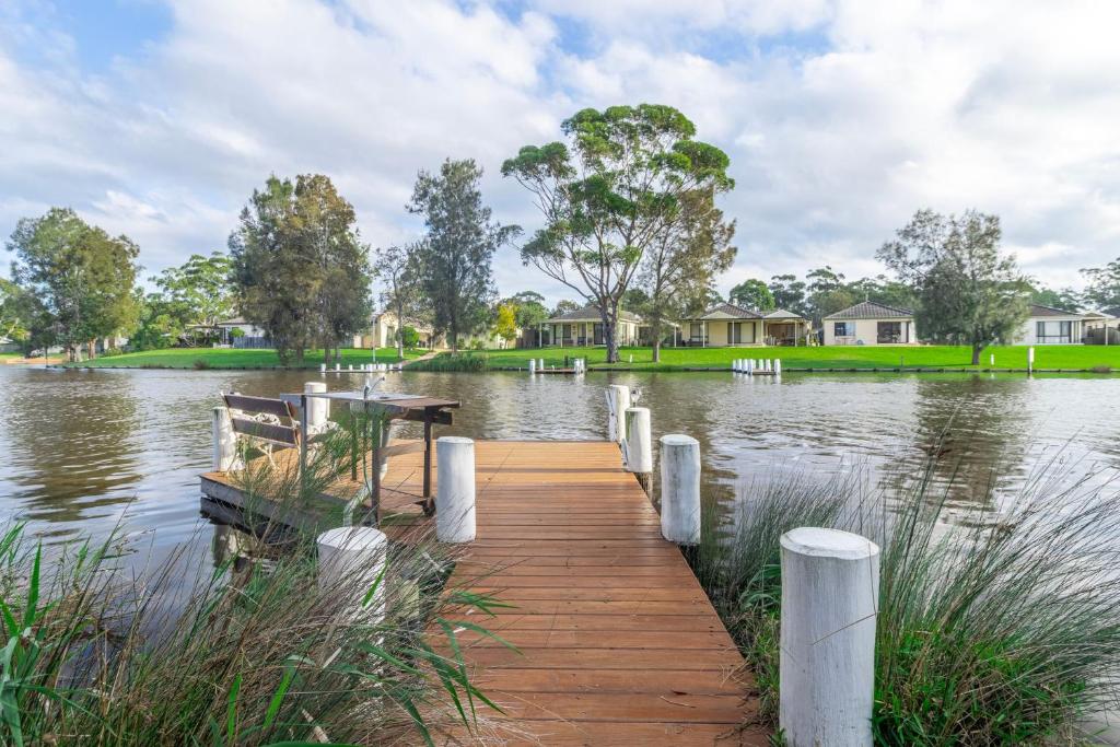 a dock in the middle of a lake with houses at Waterfront on Plover in Sussex inlet