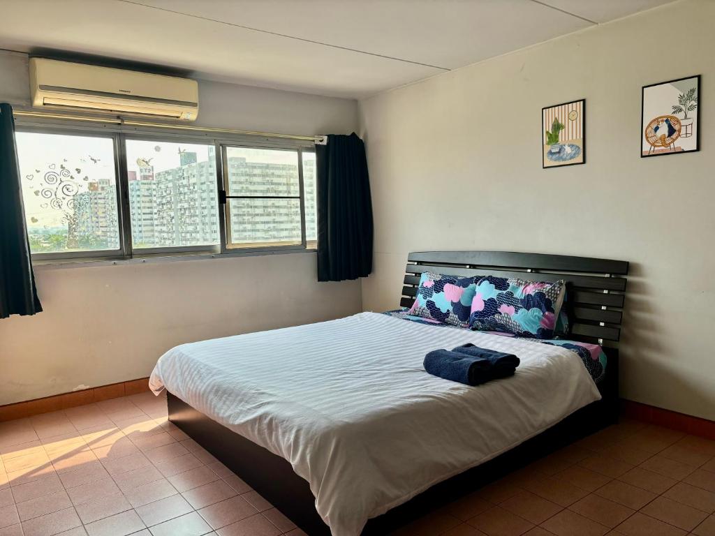 um quarto com uma cama num quarto com duas janelas em Condo popular T8 fl.8.2 em Thung Si Kan