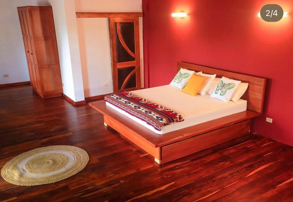 Cama en habitación con pared roja en Kudos club en Las Lajas