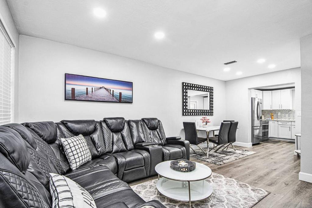a living room with a black leather couch and a table at Rachaels Upscale Two Bedrooms Luxury Home in Fort Lauderdale