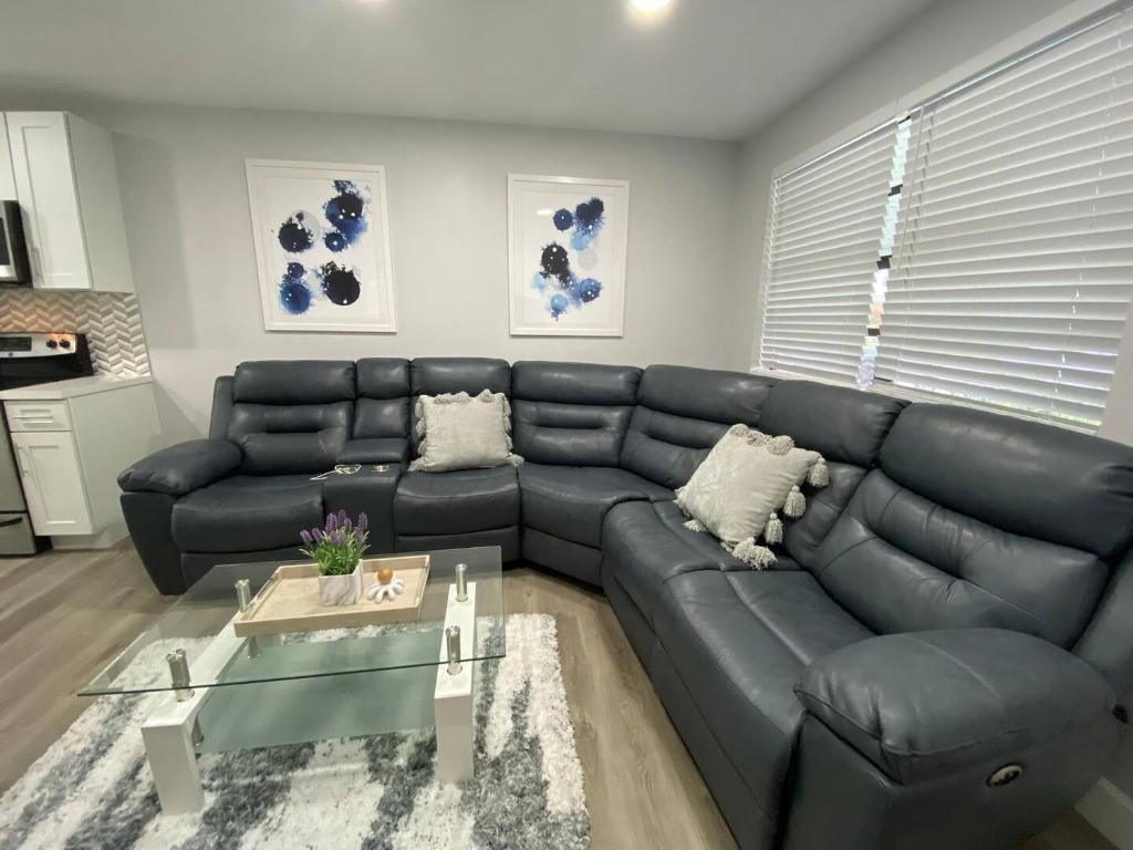 a living room with a black leather couch and a table at Rachaels Upscale 3 Bedrooms Luxury Home in Fort Lauderdale