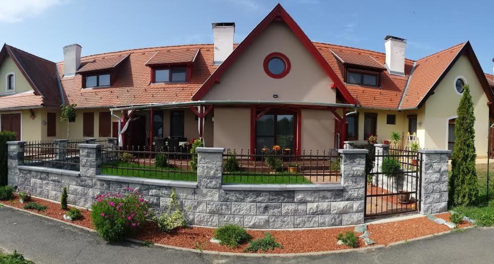 una casa con una valla de ladrillo delante de ella en Boróka Apartman Lenti en Lenti