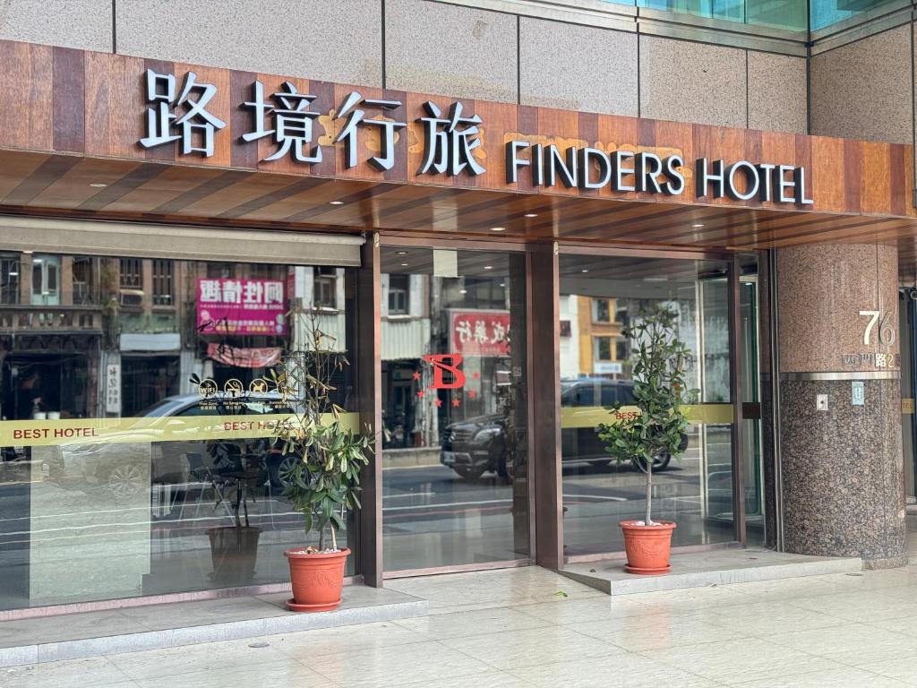 a hotel with two potted plants in front of it at 路境行旅 台南西門館 Finders Hotel Tainan Ximen in Tainan