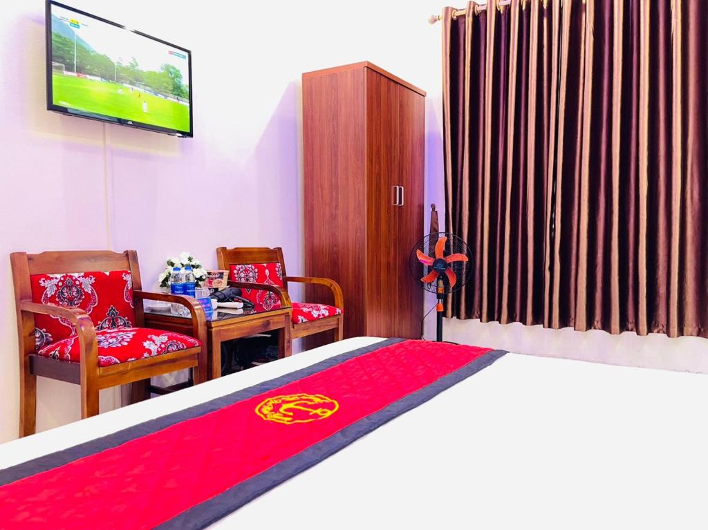 ein Schlafzimmer mit einem Bett, 2 Stühlen und einem TV in der Unterkunft TITANIC 3 HOTEL in Hậu Dương