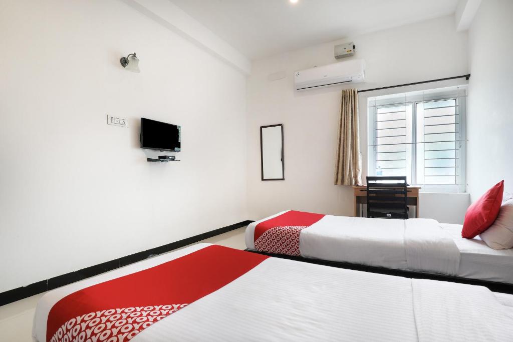 a hotel room with two beds and a window at Flagship 82361 Black Pearl Residency in Pīlamedu