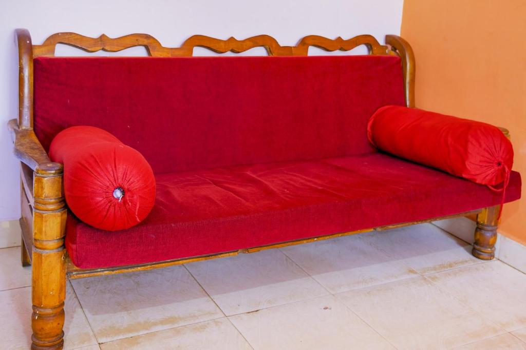 a red couch with two red pillows on it at OYO Mahamaya Holiday Inn Near Calangute Beach in Calangute