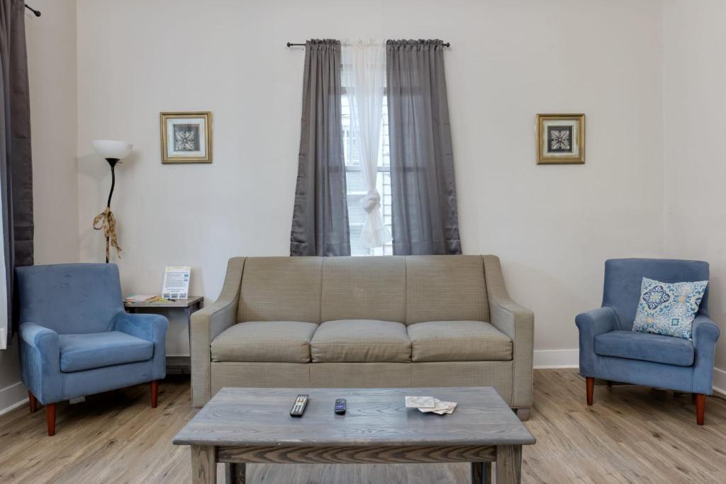a living room with a couch and two blue chairs at The Chattahoochee Cottage Walk to River & Shops in Columbus