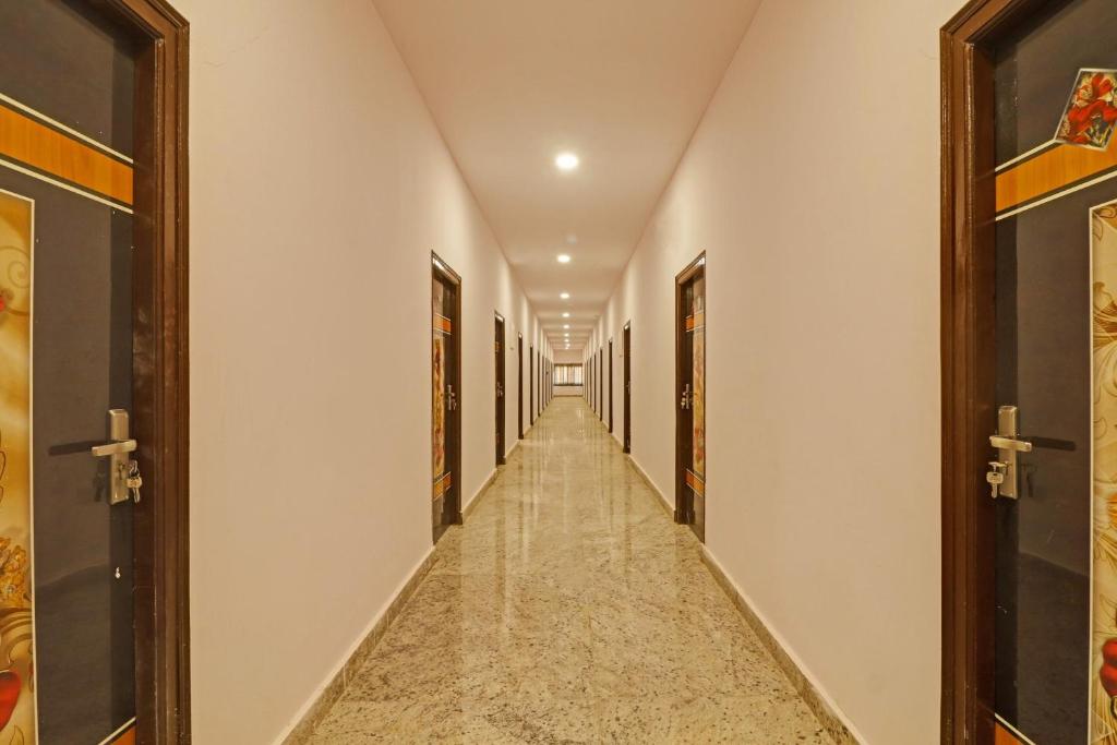 a corridor with doors and a long hallway with marble floors at Super Capital O Hotel Sai Balaji Near Golconda Fort in Hyderabad