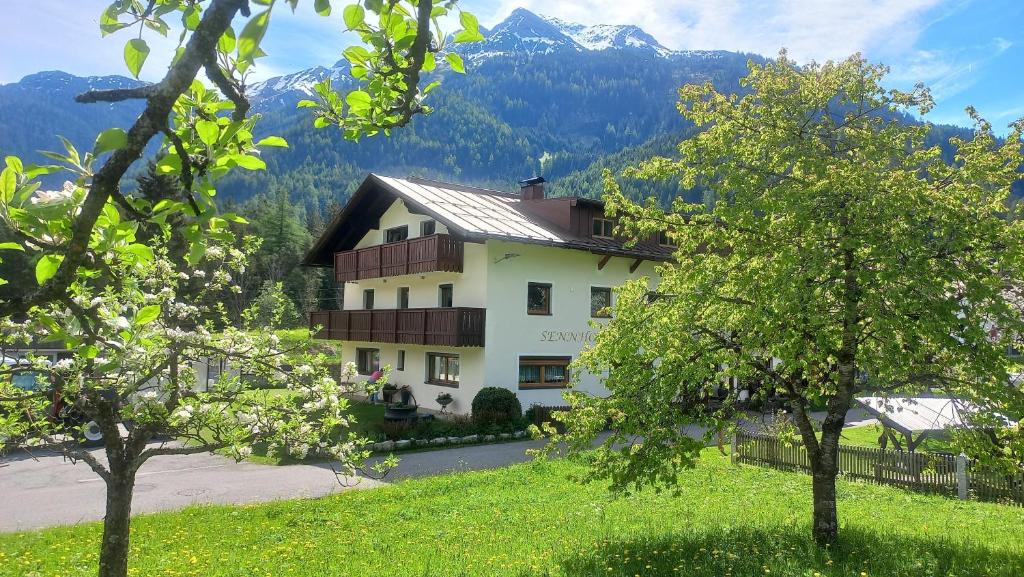 a building in the mountains with trees in the foreground at SennHOF Lechtal in Bach