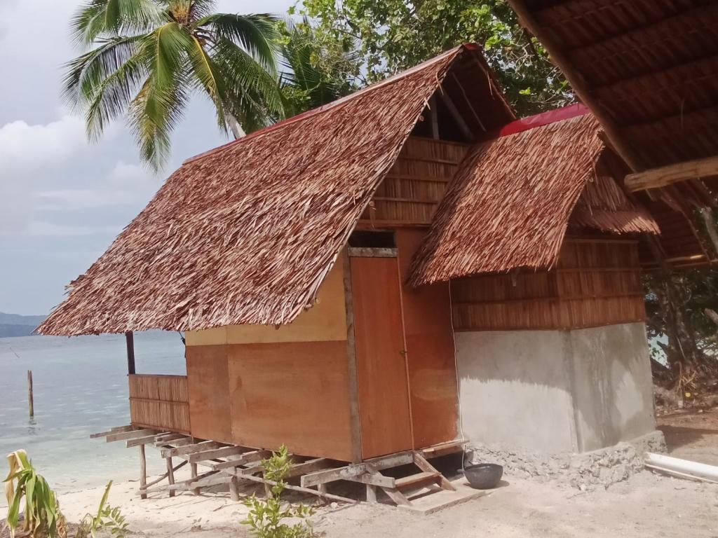 a hut on the beach with the ocean in the background at Nyande Rengkri Guest House in Kri