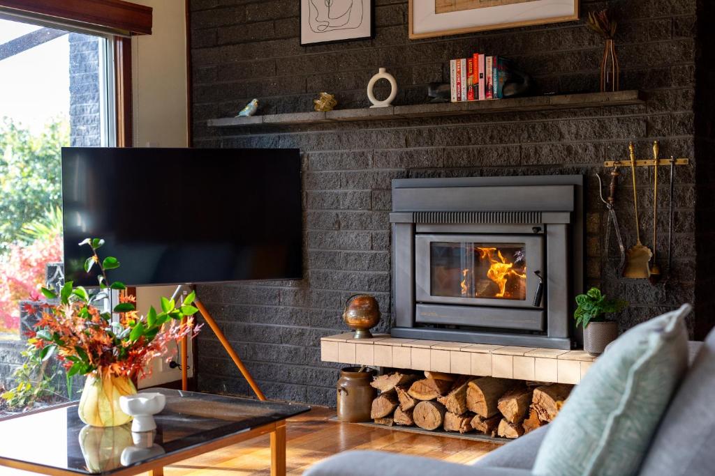 un salon avec une cheminée et une télévision dans l'établissement Stella Rose Cottage, à Rosevears