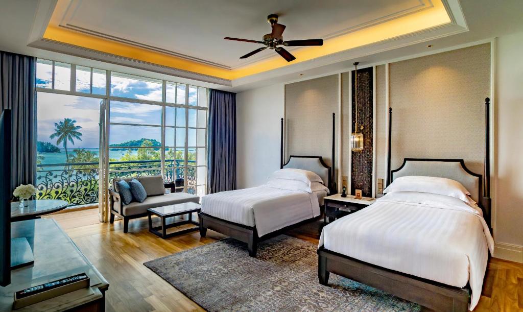 1 dormitorio con 2 camas y vistas al océano en The Danna Langkawi - A Member of Small Luxury Hotels of the World, en Pantai Kok