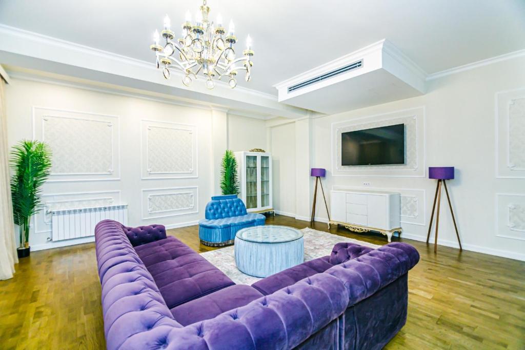 uma sala de estar com um sofá roxo e um lustre em VIP Apartment MANDARIN em Baku