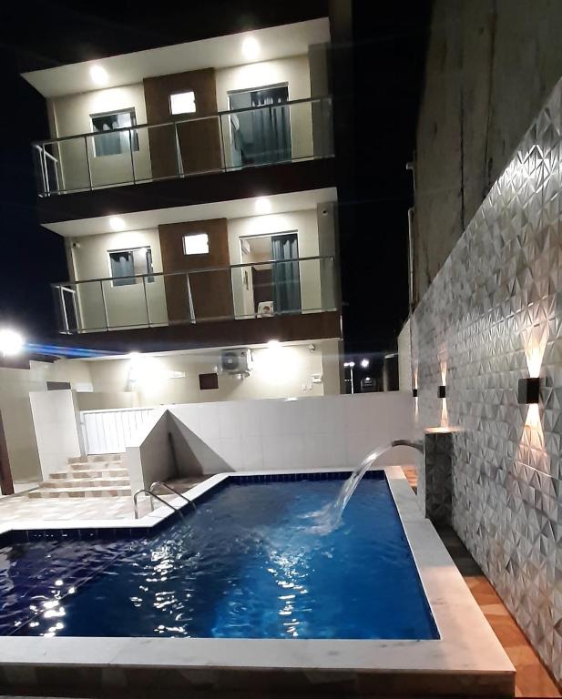 a swimming pool with a fountain in front of a building at Recanto do Mar em Peroba 02 in Maragogi