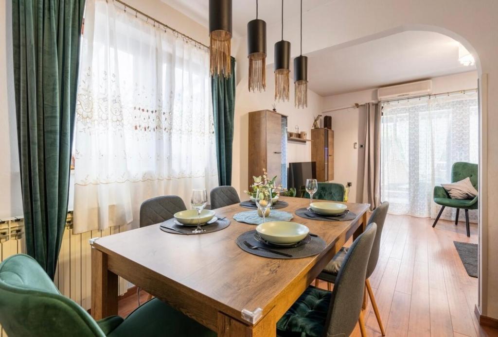 una sala da pranzo con tavolo in legno e sedie verdi di Lux apartment Barbara a Poreč (Parenzo)