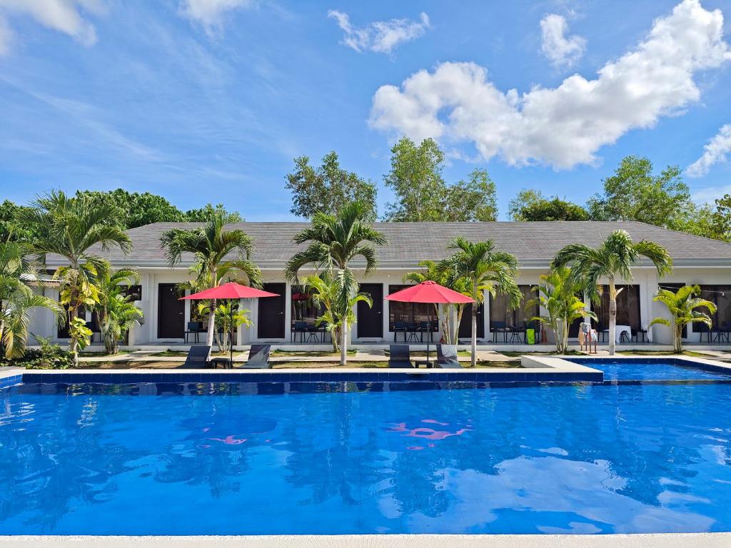 a large swimming pool in front of a building with palm trees at OHANA, Panglao Resort. in Panglao