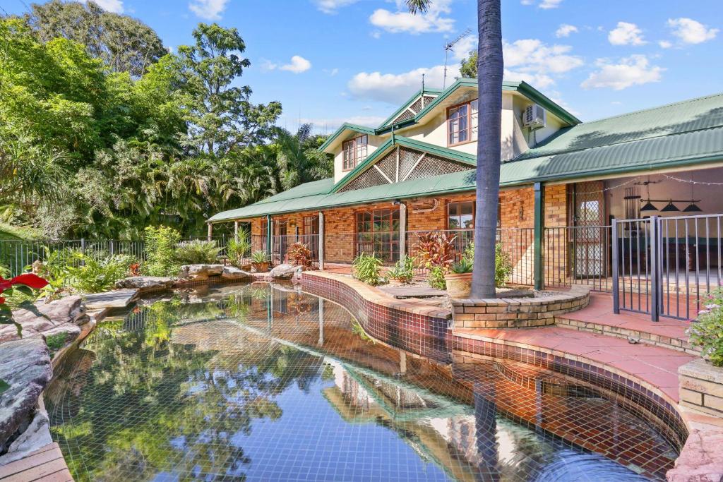 a house with a pond in front of it at Spacious 4-Bed Hinterland Luxury Escape with Pool in Gold Coast
