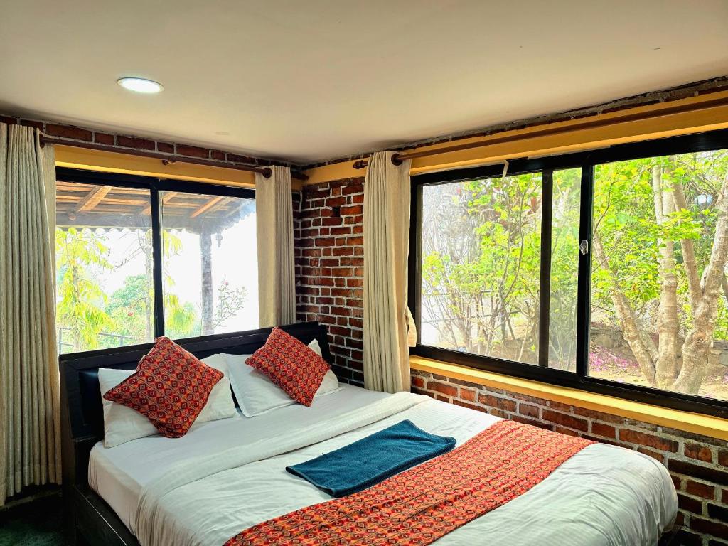 a bedroom with a bed and two large windows at Rock Garden Resort in Pokhara