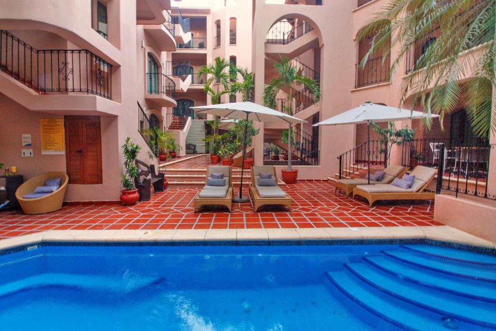 una piscina con sillas y sombrillas junto a un edificio en Acanto Hotel Playa del Carmen, Trademark Collection by Wyndham en Playa del Carmen