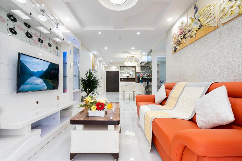 ein Wohnzimmer mit einem orangenen Sofa und einem TV in der Unterkunft Three Bedroom Scenic Valley in Ho-Chi-Minh-Stadt