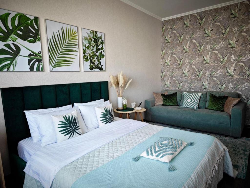 a bedroom with a large bed and a couch at Green Boutique - квартира в изумрудных оттенках на Мынбаева in Almaty