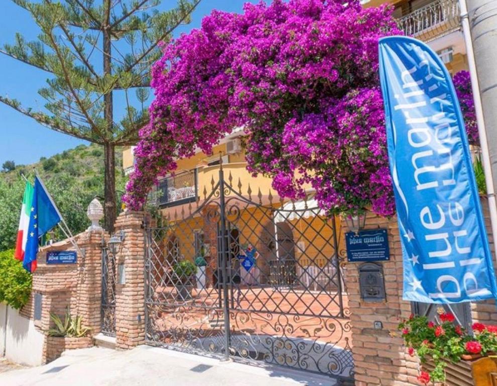 a building with purple flowers on a fence at Blue Marlin in Marina di Camerota